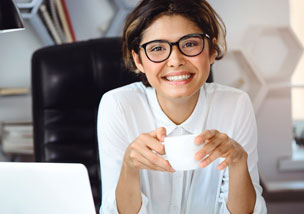smiling woman at desk with cup of coffee